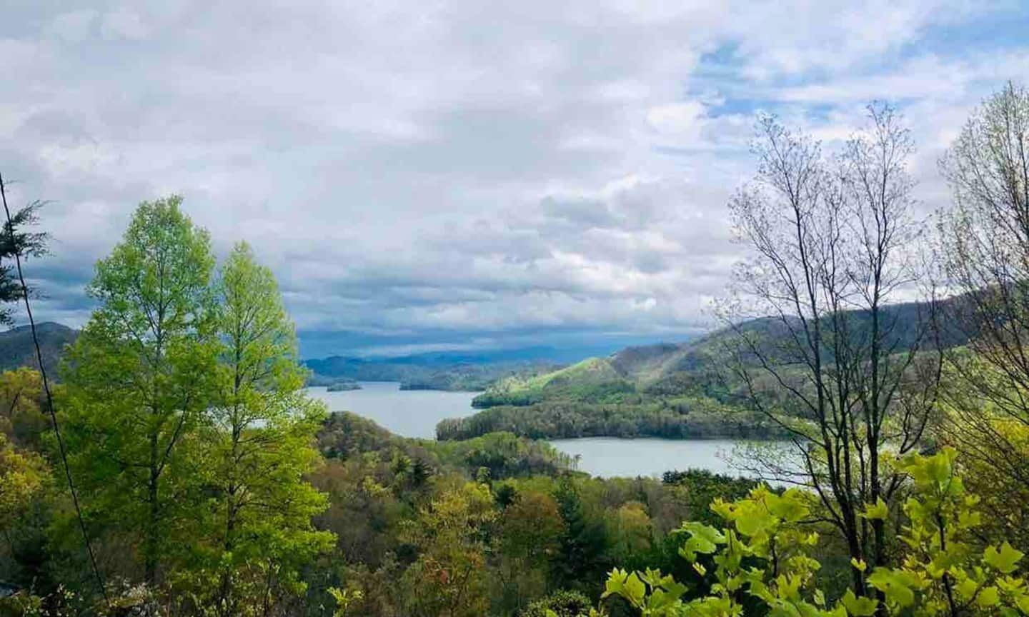 A natural landscape with a lake surrounded by hills and trees.