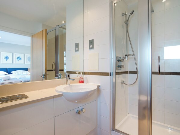 Een moderne badkamer met een douchecabine van glas, een witte wastafel en een grote spiegel.