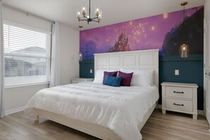 Un dormitorio con una cama grande, mesitas de noche blancas, un mural en la pared y un candelabro.
