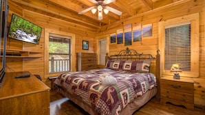 A wooden cabin bedroom with a bed, a television, a ceiling fan, and a window with blinds. - Mtn Cabin with Hot Tub, pool table, arcade, smartTVs, fast FiWi, great location! (Pigeon Forge)