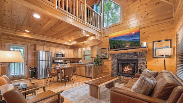 A spacious cabin interior with a dining area, kitchen, living room, and a fireplace. - Mtn Cabin with Hot Tub, pool table, arcade, smartTVs, fast FiWi, great location! (Pigeon Forge)
