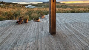 Una terraza de madera con vista a un río y colinas al fondo.