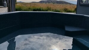 Una piscina con vistas a un campo cubierto de césped y colinas lejanas.
