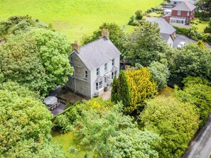 Une vue aérienne d’une maison entourée d’une végétation luxuriante et d’un petit étang.
