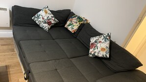 Un sofá gris oscuro con un respaldo bajo y dos cojines estampados con motivos florales.
