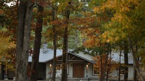 Een chalet met een stenen schoorsteen, een houten deur en een veranda met een bank.
