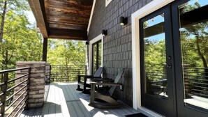 A modern outdoor deck with a stone accent wall, a wooden pergola, and a seating area with a table and chairs. - Lakeside | Hot Tub | Kayaks | Fishing (MENA)