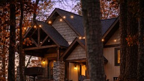 A rustic cabin with a stone foundation, wooden beams, and a porch with outdoor seating. - Lakeside | Hot Tub | Kayaks | Fishing (MENA)