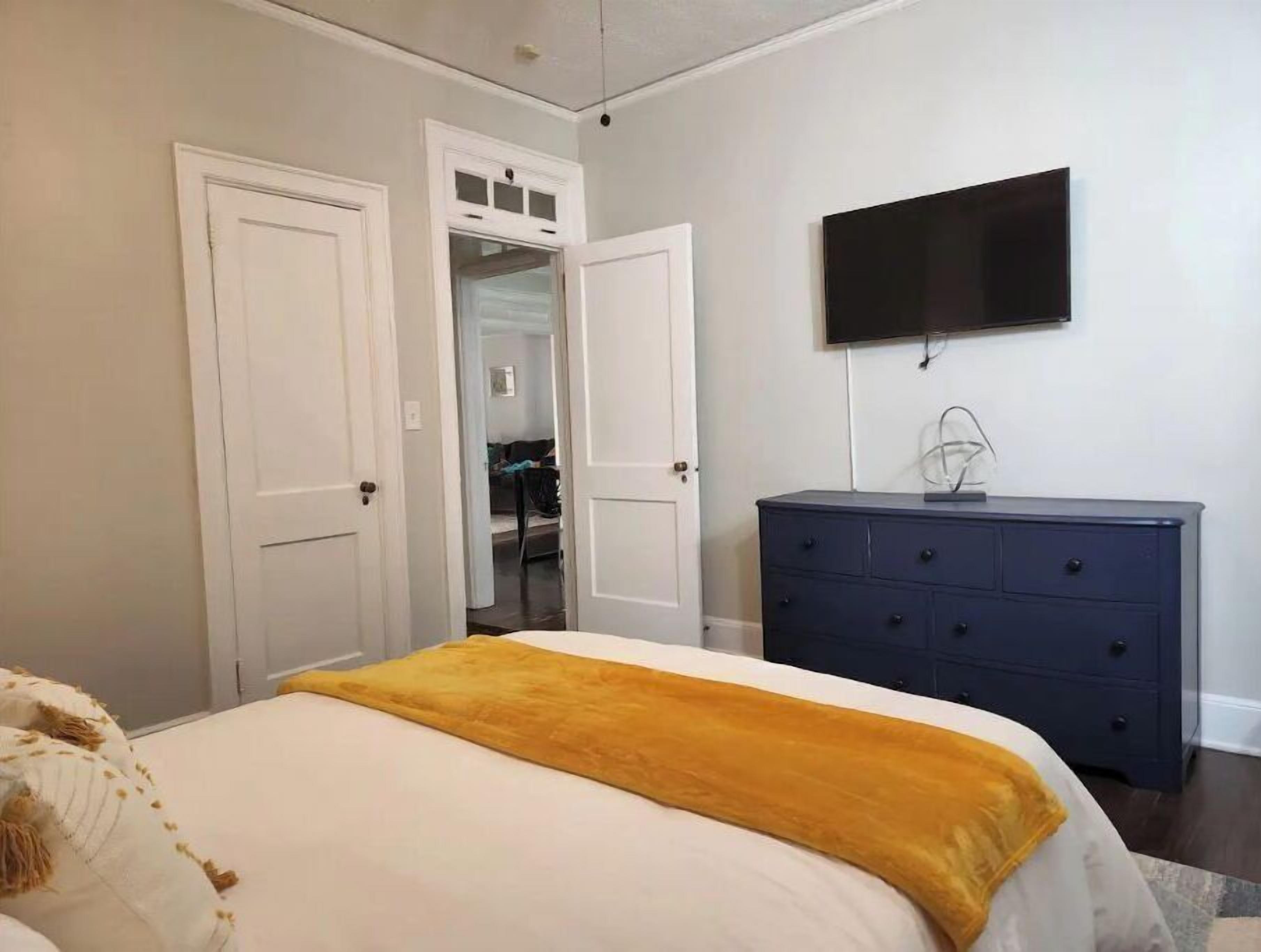 A bedroom with a bed, a dresser, and a TV mounted on the wall.