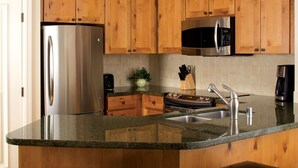 Una cocina con armarios de madera, electrodomésticos de acero inoxidable, encimeras de granito y horno empotrado.