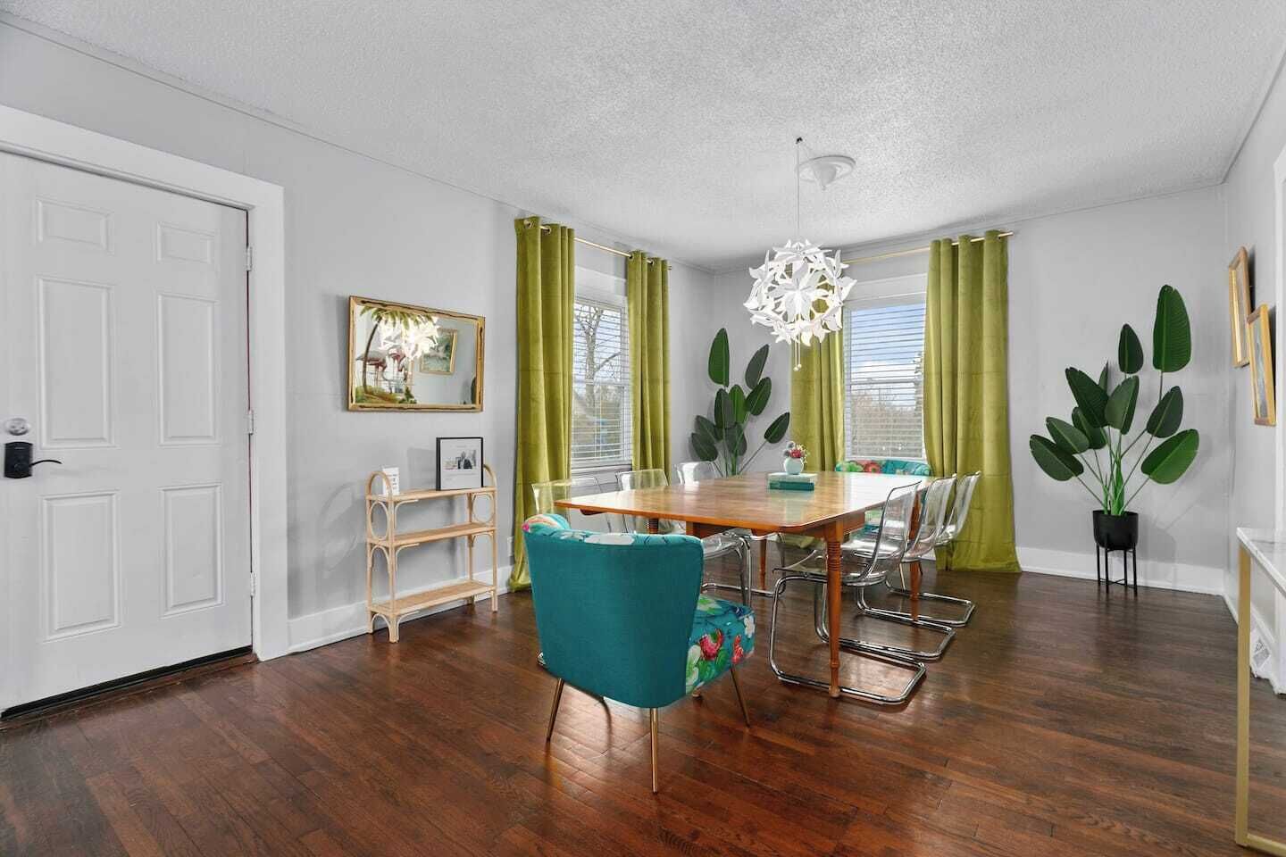 A dining area with a wooden table, teal chairs, and a chandelier.