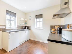 Een moderne keuken met witte kasten, een zwart aanrecht en een rvs afzuigkap.
