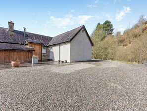 Une maison avec une allée en gravier, une porte en bois et un mur en pierre.