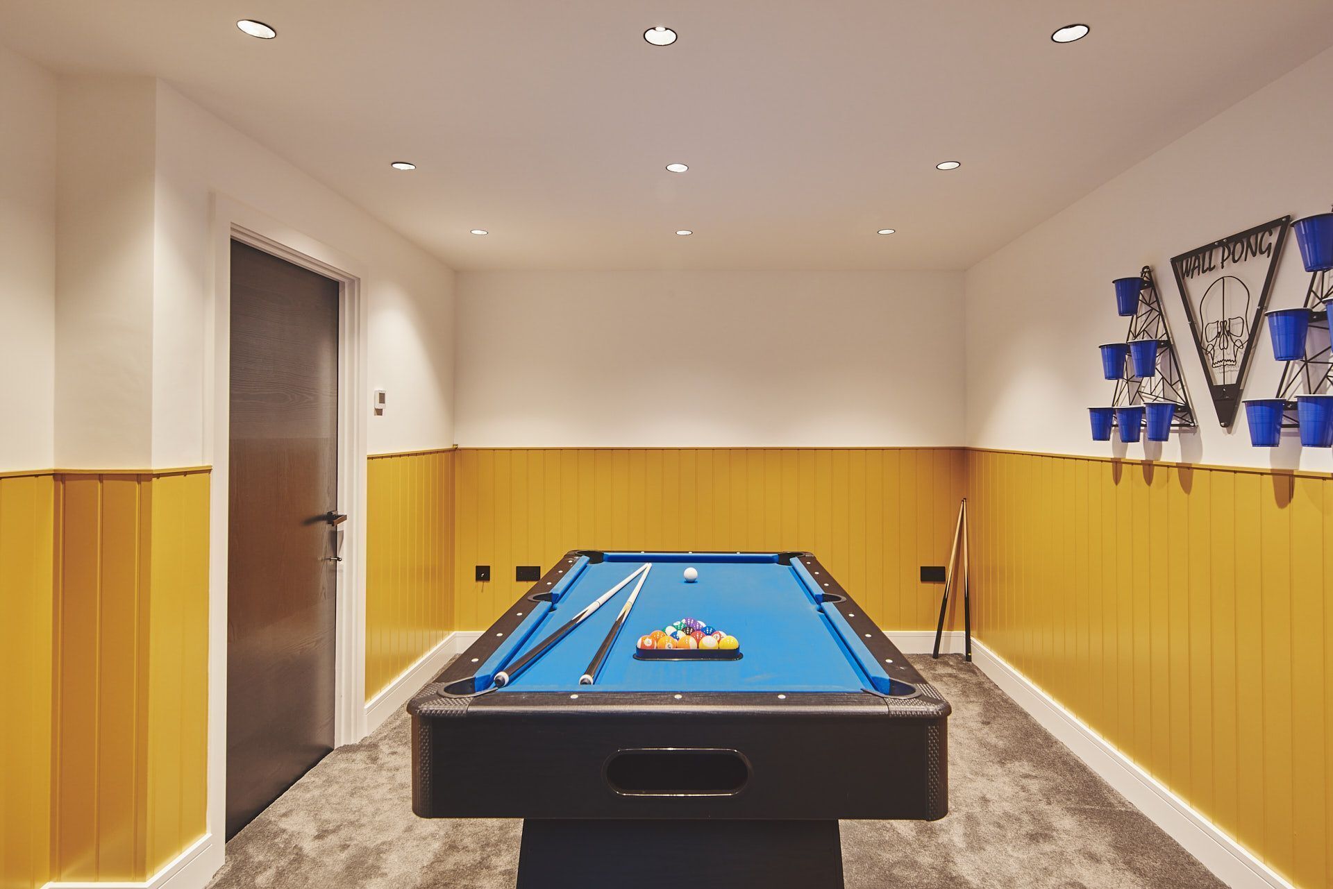 A pool table in a room with yellow walls and a door on the left.