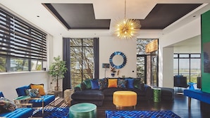 A modern living room with a large sofa, blue and yellow ottomans, and a unique chandelier. - Reservoir View -  a modern home that sleeps 8 guests  in 4 bedrooms (Cheddar)