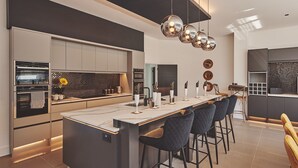 A modern kitchen with a central island, bar stools, and a dining area with a high table. - Reservoir View -  a modern home that sleeps 8 guests  in 4 bedrooms (Cheddar)