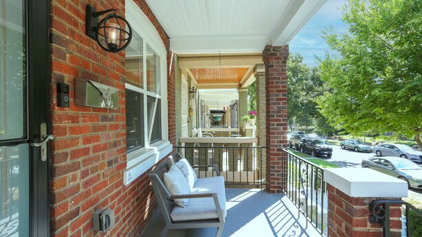 A brick building with a balcony, a rocking chair, and a view of parked cars and trees. - Private Patio + Parking + Near H Street & DC Attractions  Great for Families! (Washington)