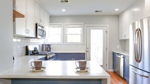 A modern kitchen with white cabinets, a stainless steel refrigerator, and a central island with two cups. - Private Patio + Parking + Near H Street & DC Attractions  Great for Families! (Washington)