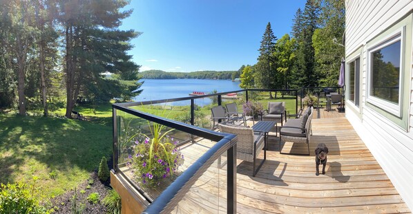 A deck with outdoor furniture, a dog, and a view of a lake. - "Farm House" on Lake of Bays-Muskoka (Waterfront) (Huntsville)