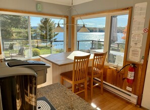 A cozy kitchen with a large window overlooking a lake, wooden furniture, and a fire extinguisher on the wall. - "Farm House" on Lake of Bays-Muskoka (Waterfront) (Huntsville)