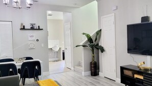 Una sala de estar moderna con televisor, comedor y una escalera que lleva a otra habitación.