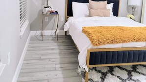 Un dormitorio con una cama, una mesita de noche, una lámpara, un espejo y un cuadro en la pared.
