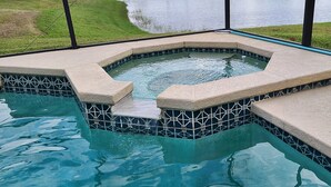 A hot tub with a tiled border and a view of a lake. - 5 bedroom lakefront home w/ large private pool & spa - Close to WDW & Universal (Kissimmee)