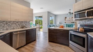 A modern kitchen with dark wooden cabinets, stainless steel appliances, and a granite countertop. - 5 bedroom lakefront home w/ large private pool & spa - Close to WDW & Universal (Kissimmee)