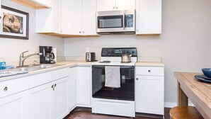A compact kitchen with white cabinets, a microwave, a stove, and a kettle. - This house is a 2 bedroom(s), 1 bathrooms, located in Frankfort, KY. (Frankfort)