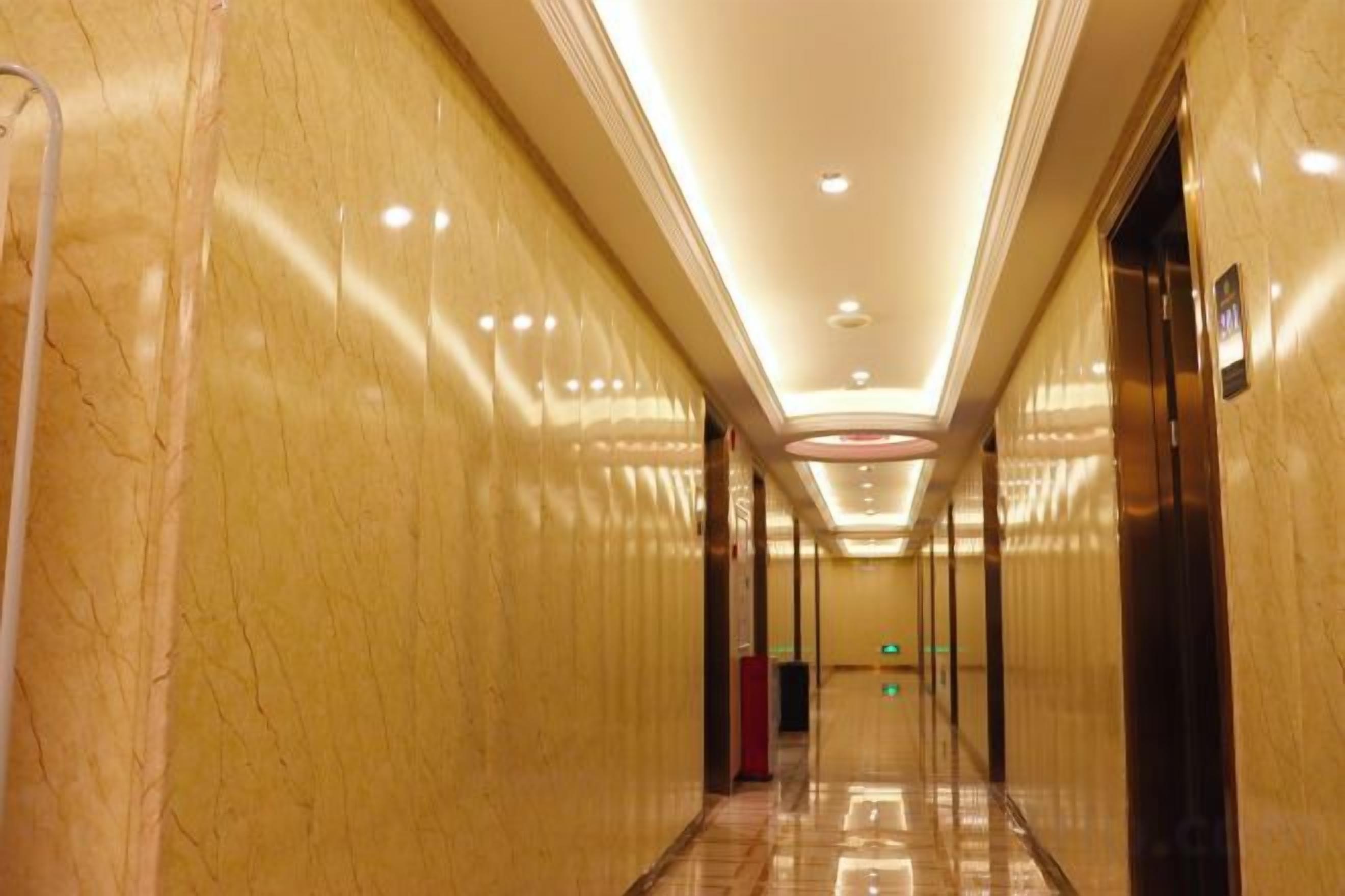 A corridor with marble walls, a polished floor, and an elevator on the right.