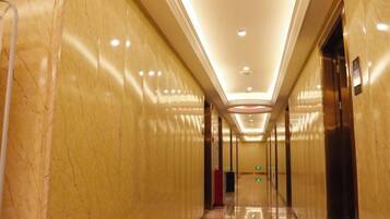 A corridor with marble walls, a polished floor, and an elevator on the right.