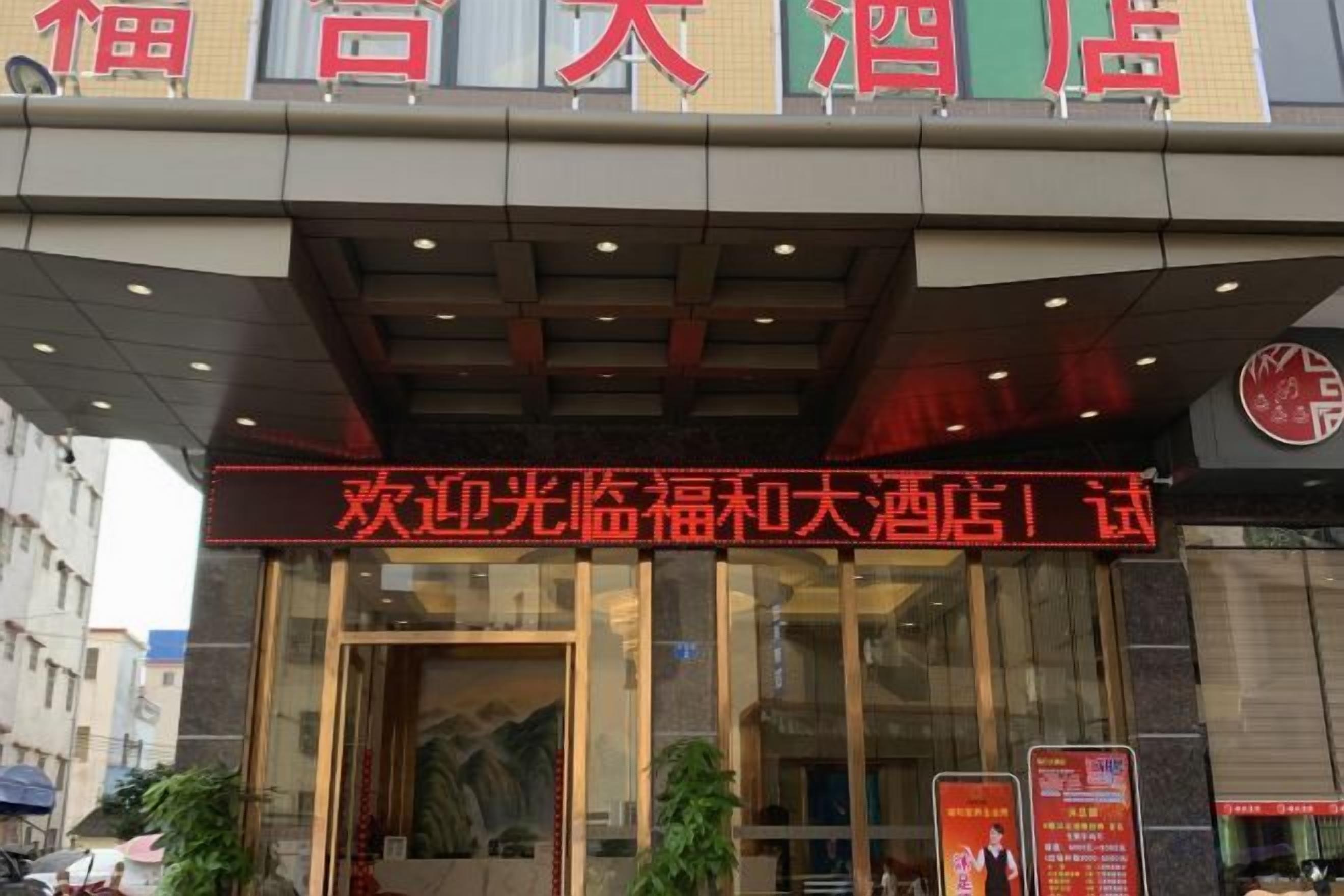 A hotel entrance with a red signboard and glass doors.