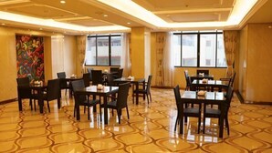 A hotel dining area with multiple tables and chairs, large windows, and a patterned floor. - Fuhe Hotel (Guangzhou)