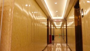 A corridor with marble walls and a polished floor, leading to an elevator. - Fuhe Hotel (Guangzhou)