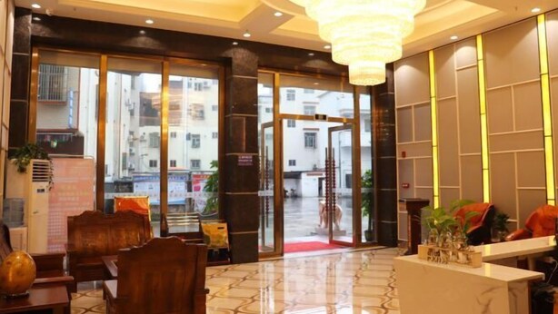 A hotel lobby with a reception desk, seating area, and large windows offering a view of the street. - Fuhe Hotel (Guangzhou)