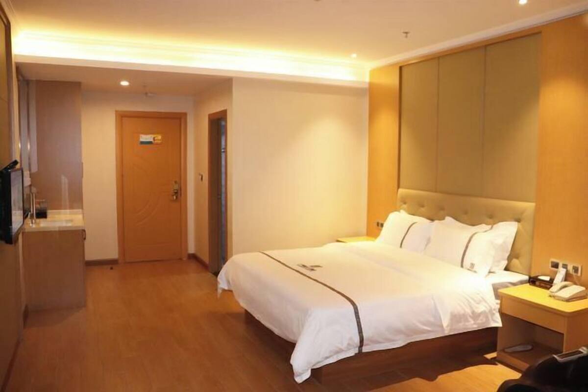 A hotel room with a bed, bedside table, and a wooden wardrobe.