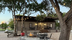 An outdoor patio with a barbecue grill, seating area, and string lights.