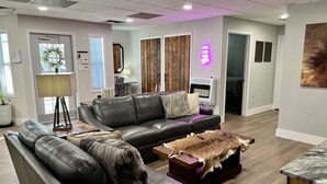 A modern living room with a leather sofa, a coffee table with a fur throw, and a wooden accent wall.