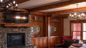A cozy living room with a stone fireplace, wooden shelves, and a comfortable seating area.