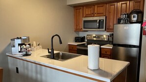 A modern kitchen with a central island, stainless steel appliances, wooden cabinets, and a built-in microwave.