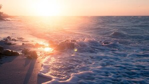 Een strand met golven bij zonsondergang.