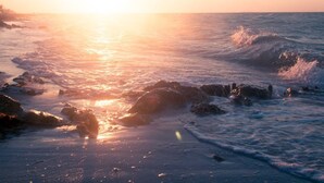 Una spiaggia con onde e rocce al tramonto.