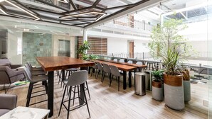 A modern office space with a long wooden table, multiple chairs, and potted plants. - Casa Magnifica 1 Bedroom Penthouse (Puerto Vallarta)