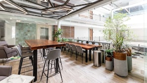 A modern office space with a long wooden table, multiple chairs, and potted plants. - Casa Zapata Avida Lush Jungle-city-cathedral View! (Puerto Vallarta)
