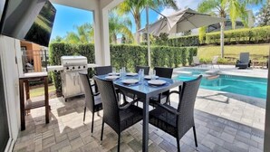 Une terrasse extérieure avec une piscine, un barbecue et des chaises de salle à manger.