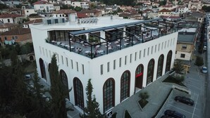 A white building with a rooftop terrace featuring outdoor seating and a restaurant. - Portik Hotel (Berat)
