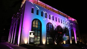 A hotel with a modern architectural design, featuring large arched windows and a brightly lit facade. - Portik Hotel (Berat)