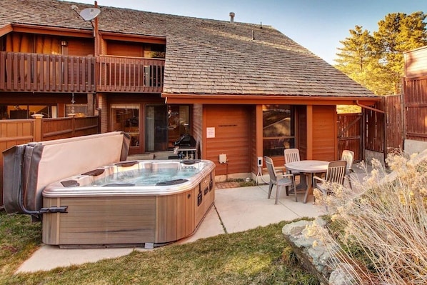 Una cabaña de madera con jacuzzi, mobiliario exterior y un patio cubierto.