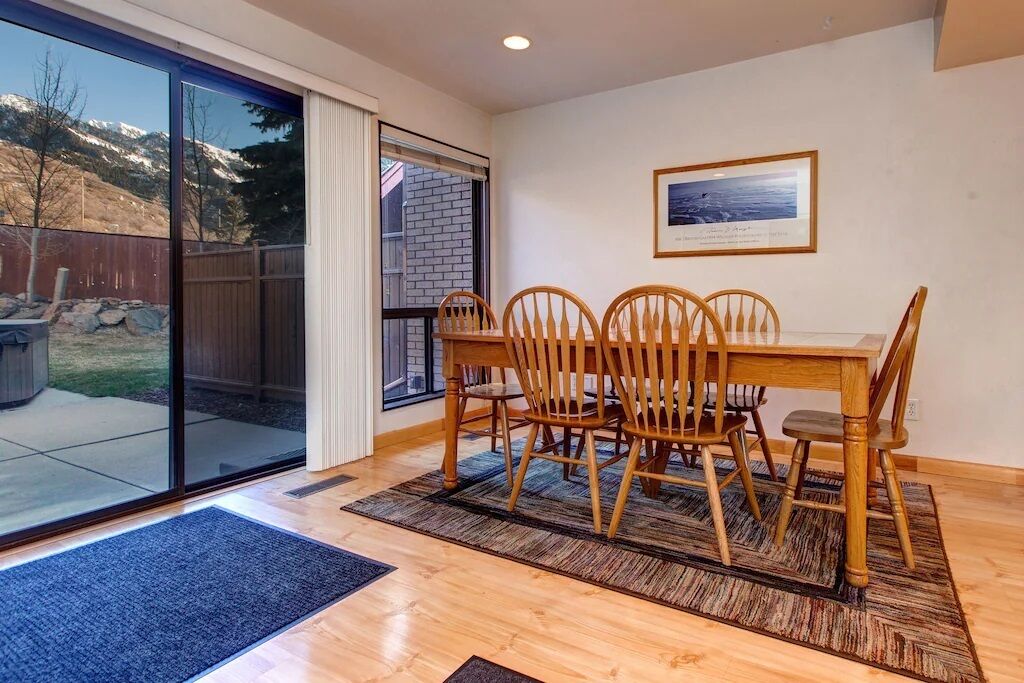 A dining area with a wooden table and chairs, a large sliding glass door leading to a backyard, and a framed picture on the wall.