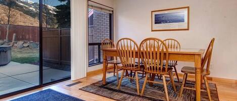 A dining area with a wooden table and chairs, a large sliding glass door leading to a backyard, and a framed picture on the wall.